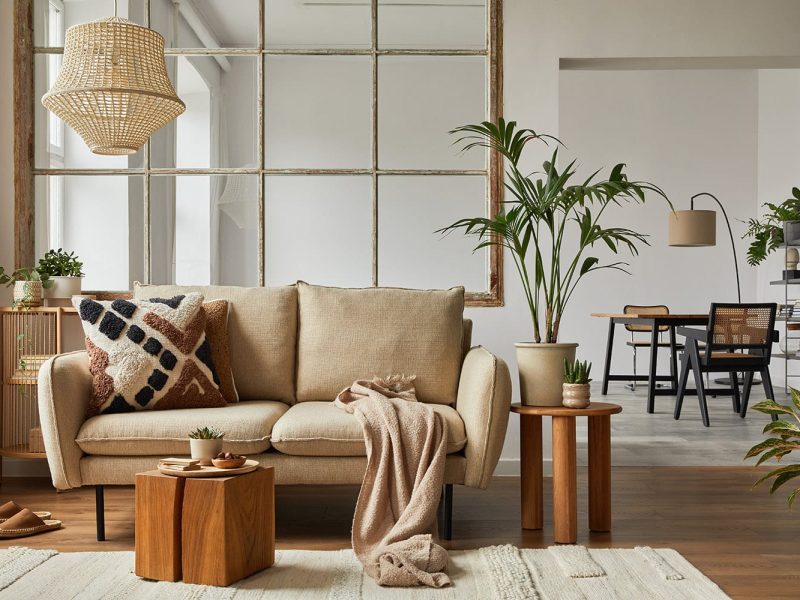 Elegant living room interior design with beige modern sofa, coffee table and creative accessories. Template. Copy space. Dining room in the background.